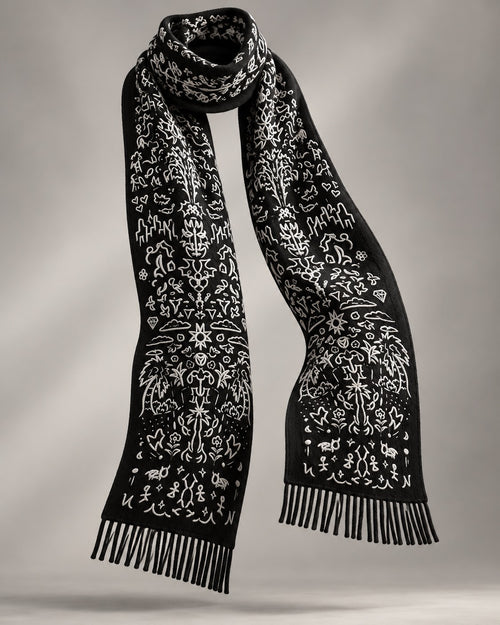 WORLDWIDE SCARF: black cashmere-merino scarf with a hand-drawn pattern in cream and twisted fringe, shown floating