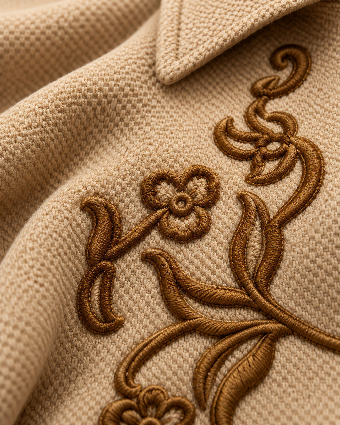 Close-up of the raised brown floral embroidery on the cream honeycomb knit